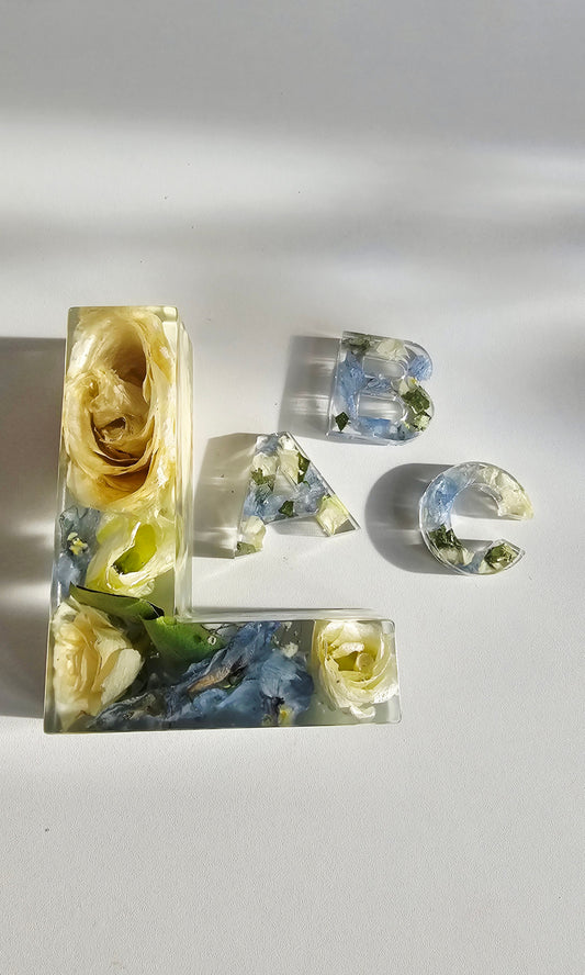 Decorative letters 'L', 'A', and 'C' made of pressed flowers on a light background