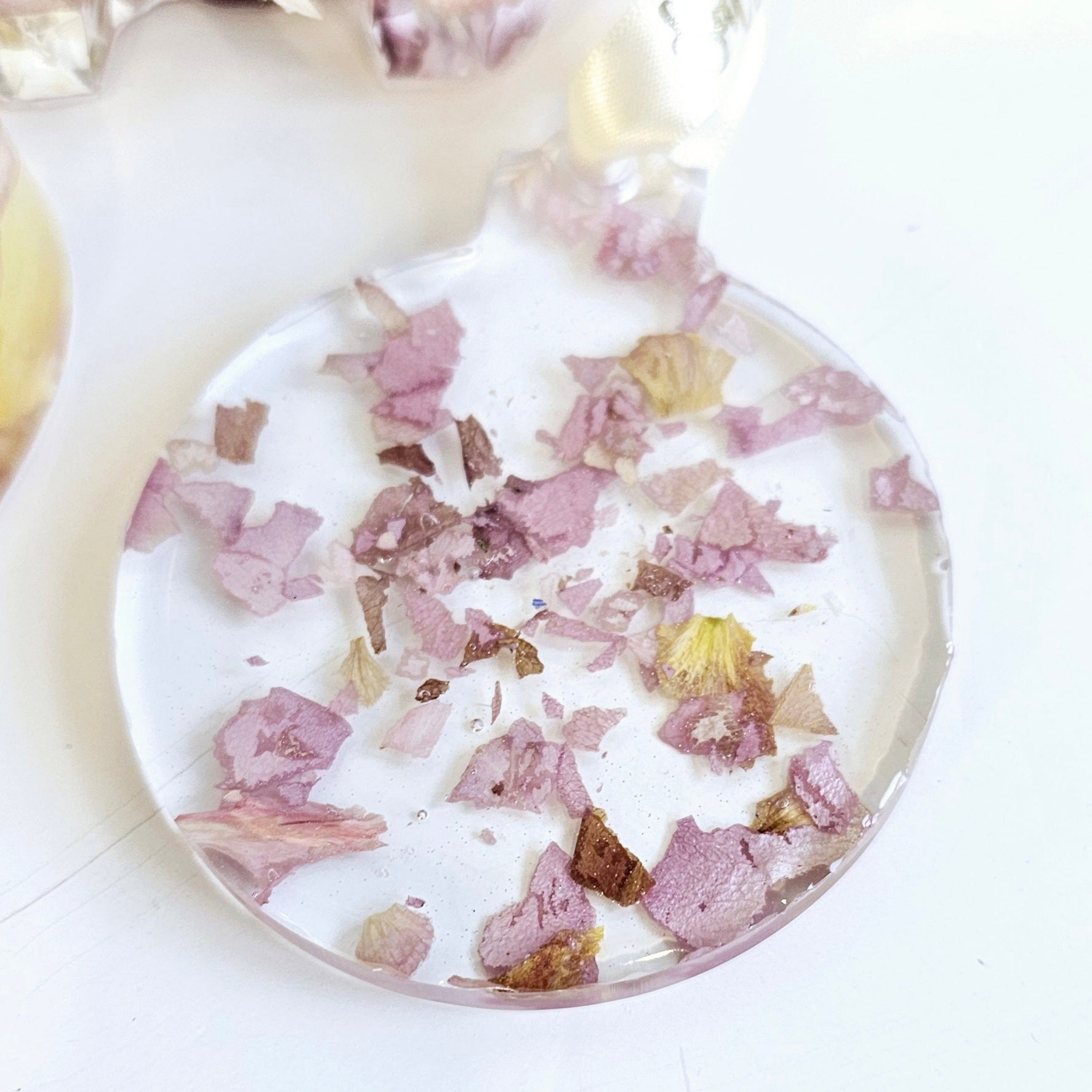 Round decorative item with pink and gold confetti on a white background