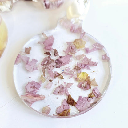 Round decorative item with pink and gold confetti on a white background