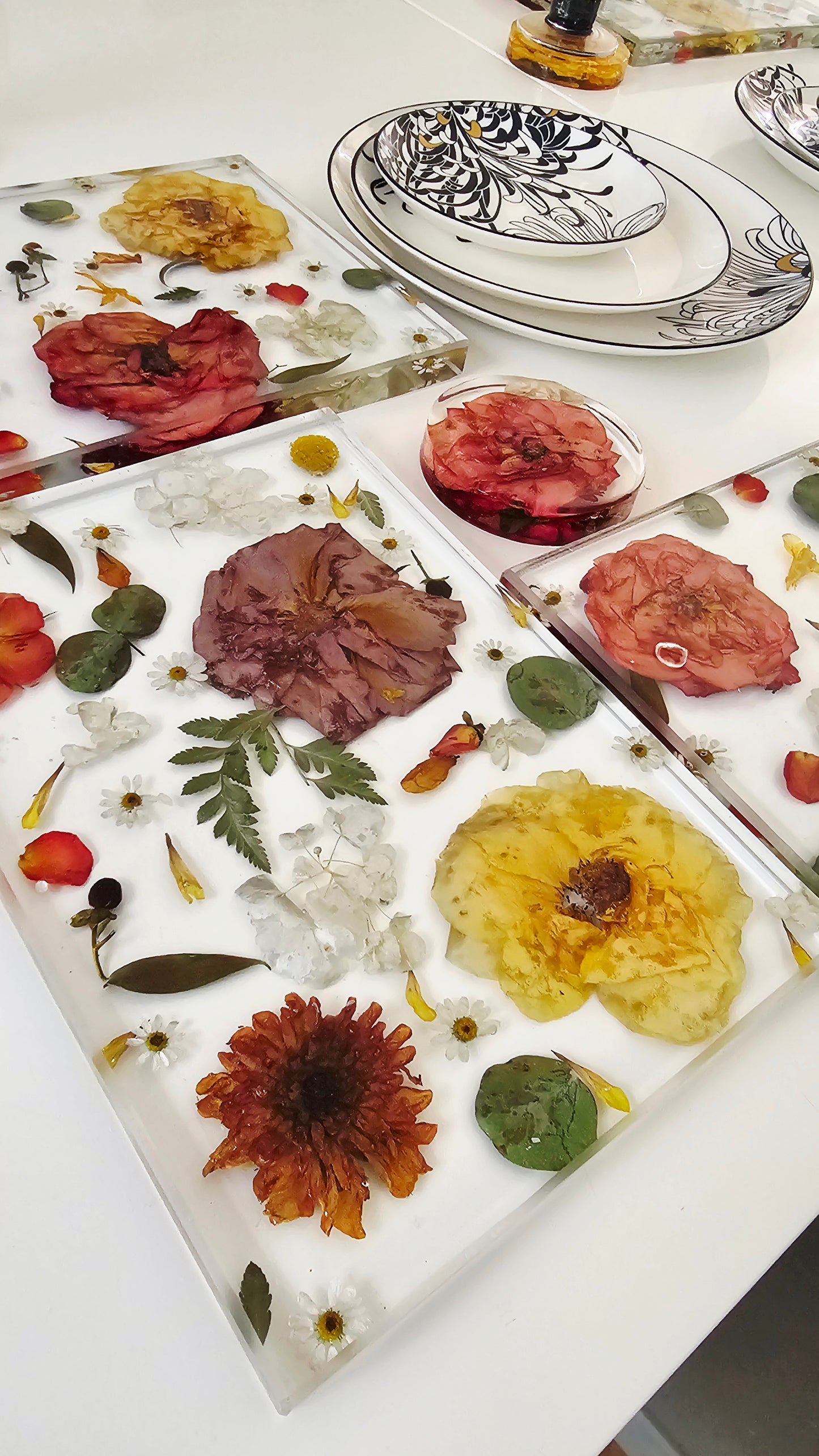 Decorative resin coasters with pressed flowers on a white surface