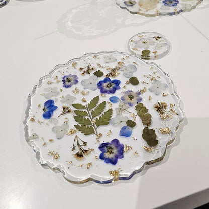 Decorative resin placemats with floral designs on a white table.