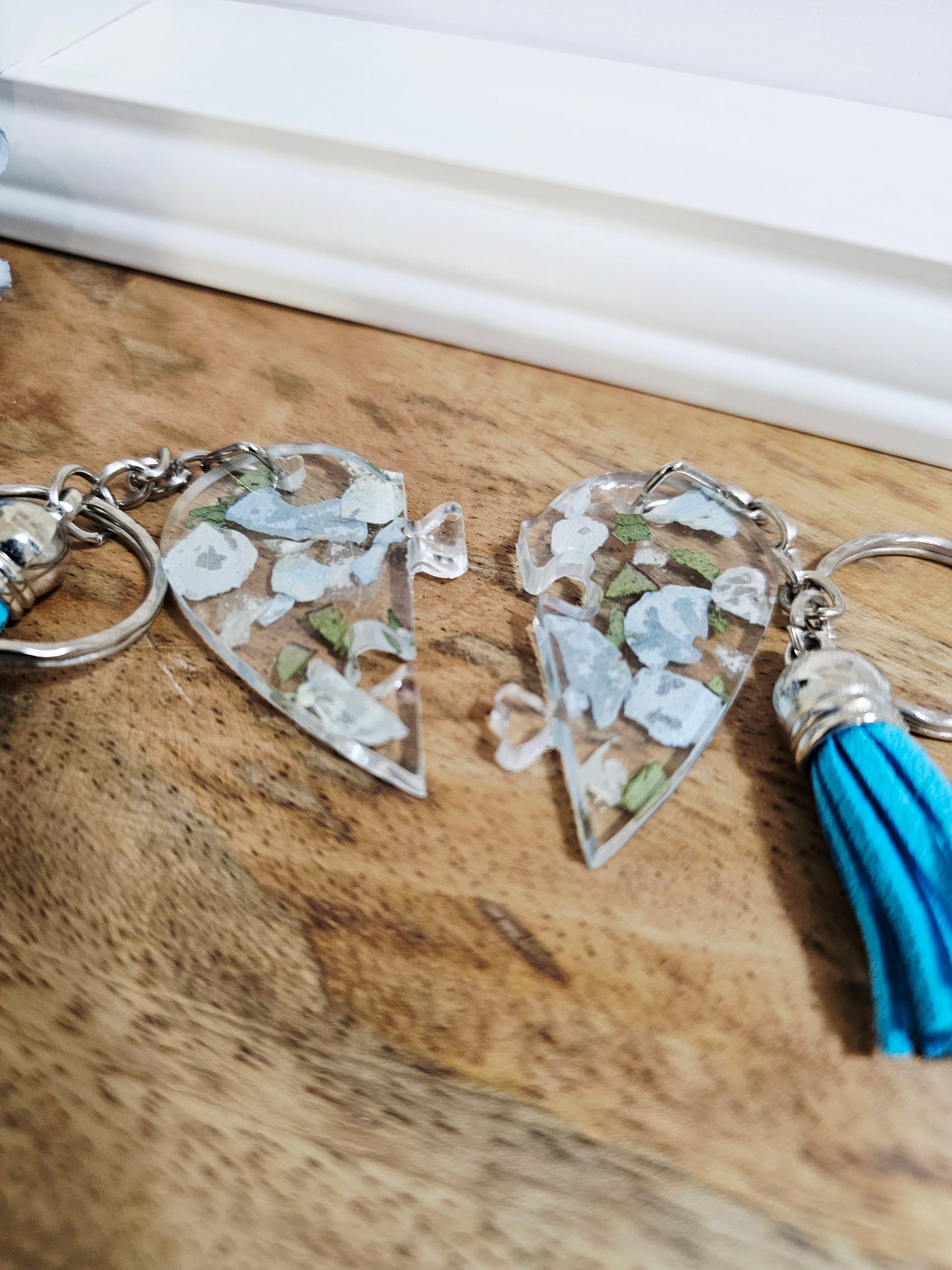 Two triangular keychains with tassels on a wooden surface