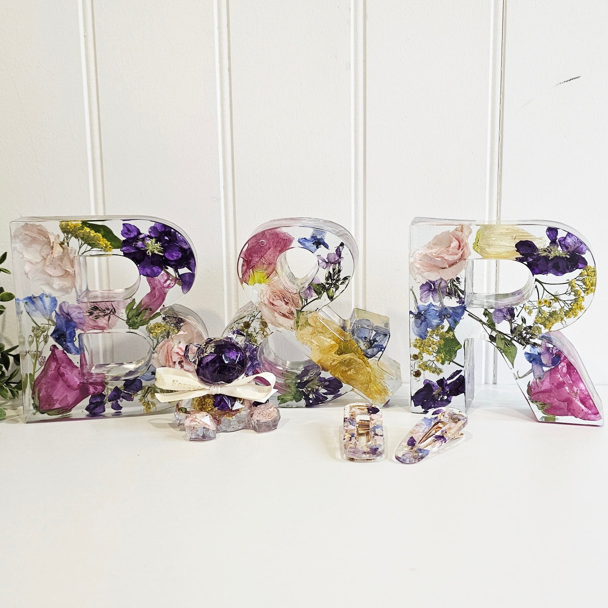 Decorative letters made of resin and preserved wedding flowers on a white surface with a white background. distant view