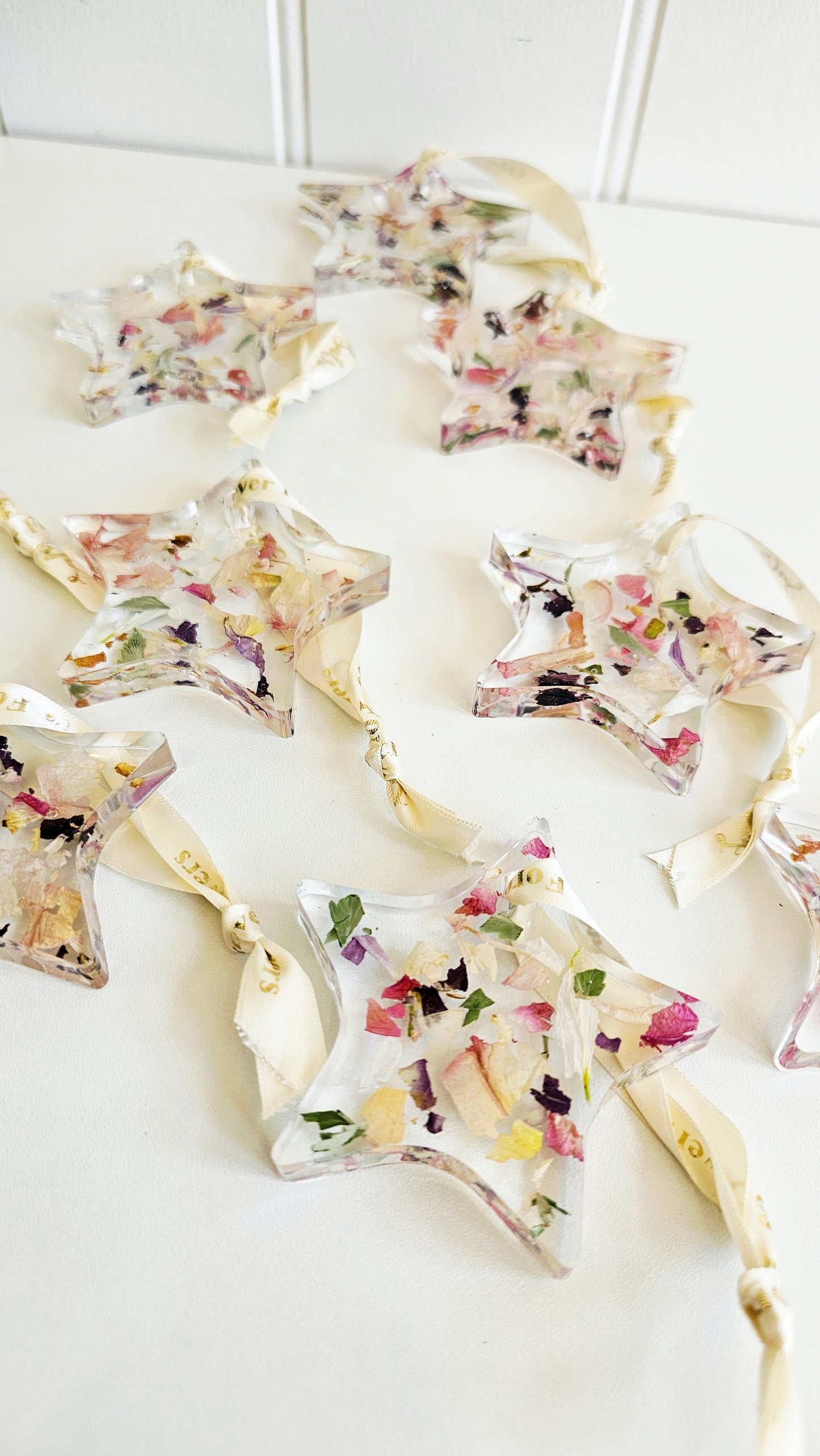 Decorative star-shaped hanging resin ornaments with floral toppings on a white surface