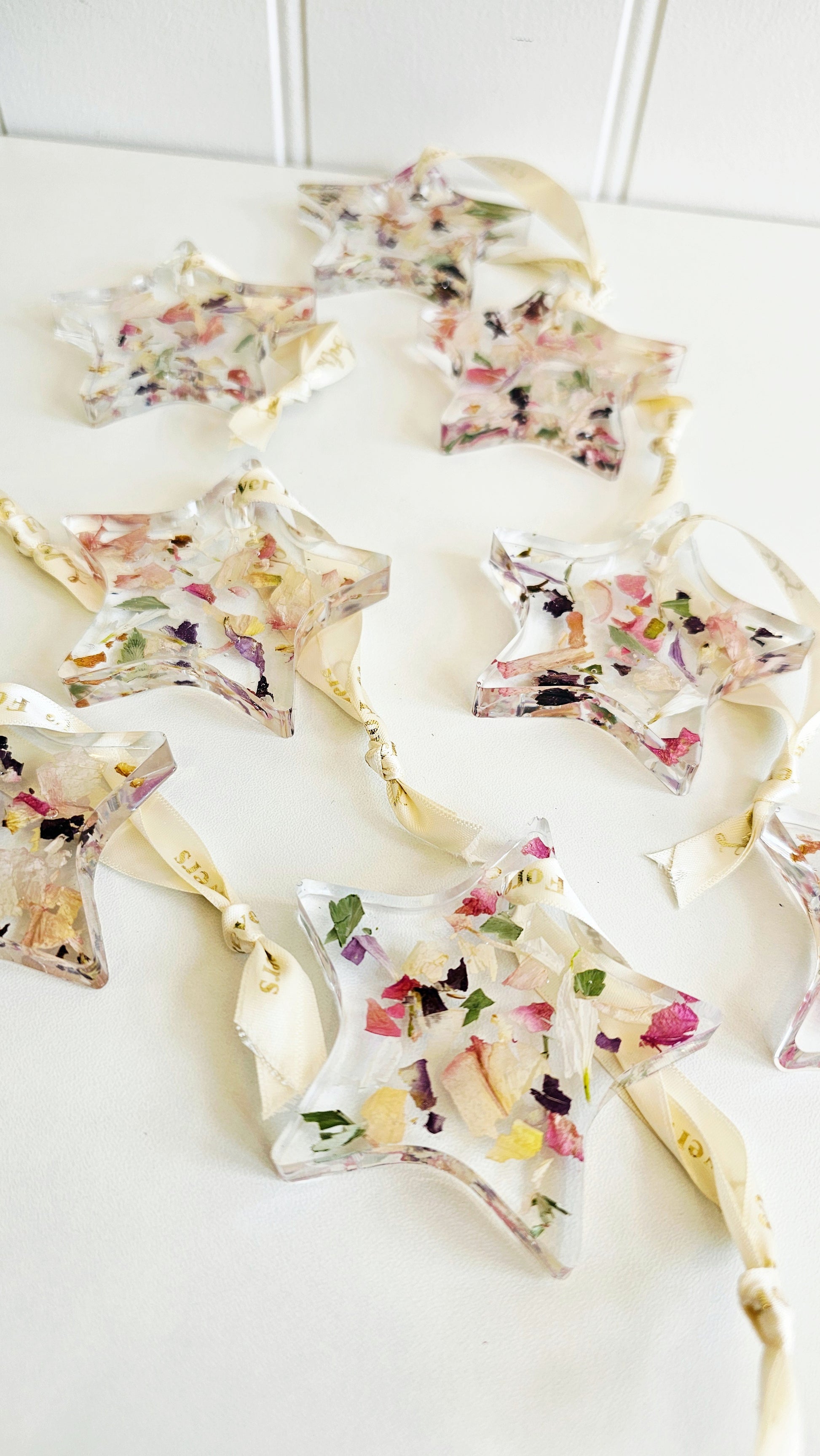 Decorative star-shaped hanging resin ornaments with floral toppings on a white surface