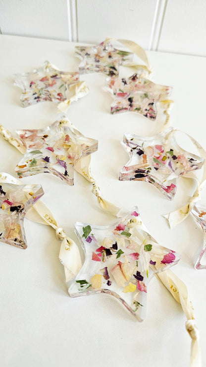 Decorative star-shaped hanging resin ornaments with floral toppings on a white surface