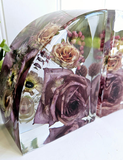 Clear resin bookends with preserved flowers including roses on a white surface