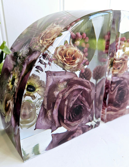 Clear resin bookends with preserved flowers including roses on a white surface