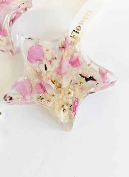 Star-shaped resin object with pink and white floral elements on a white background