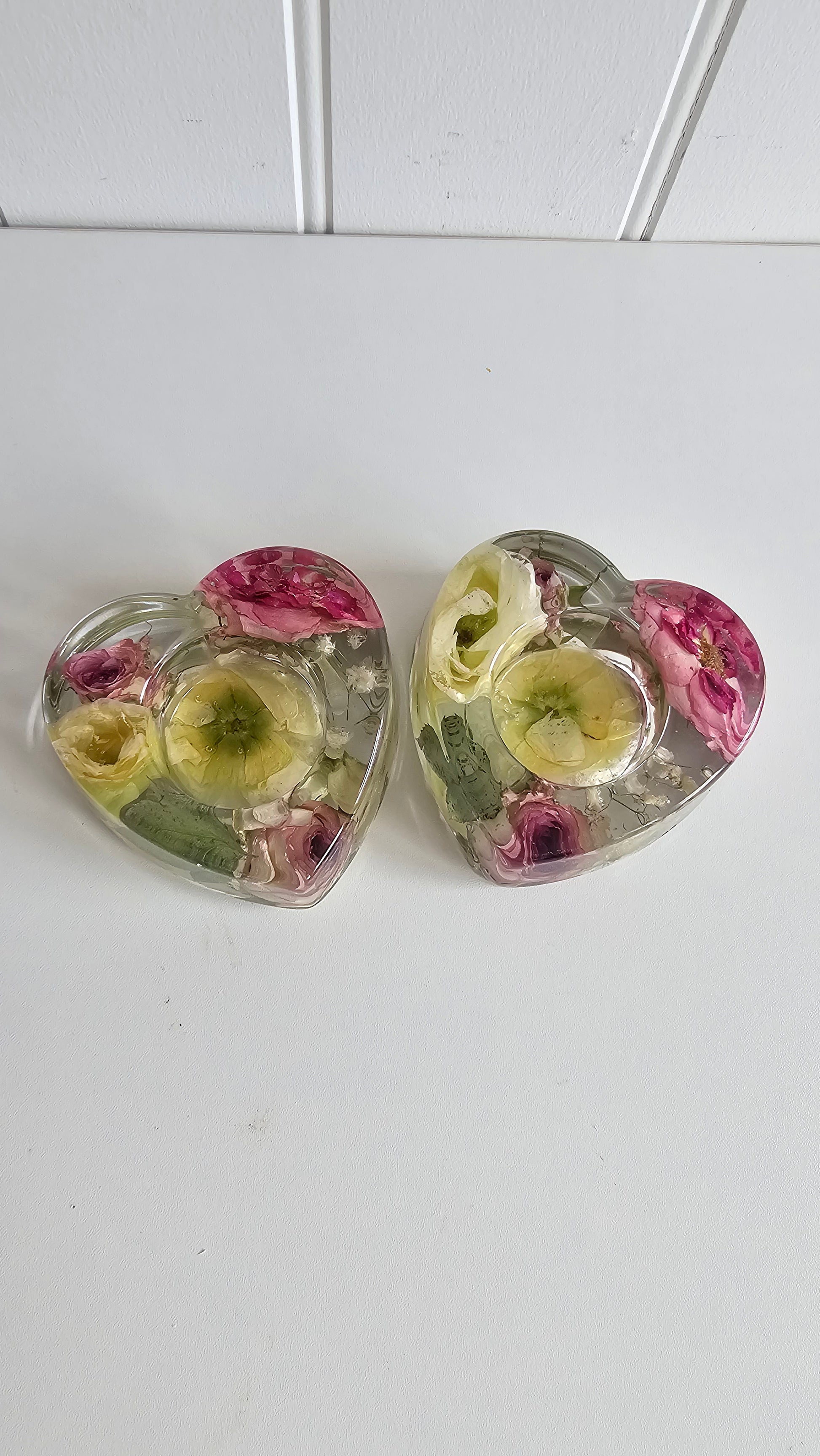 Heart-shaped resin tealight holder with embedded flowers on a white background