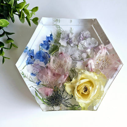 Hexagonal resin ornament with preserved flowers on a white surface