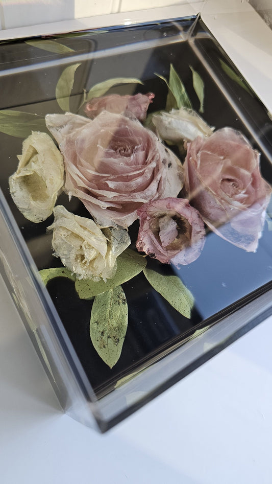 Preserved flowers in a resin and acrylic box on a white surface