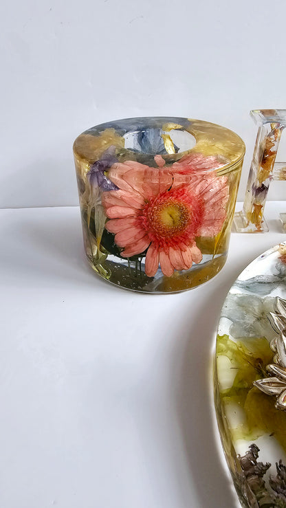 Clear candle with pink flower inside on a white surface