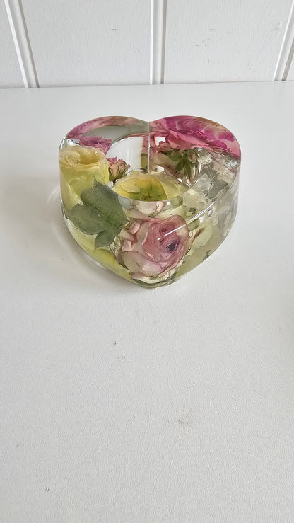 Clear resin heart tealight holder with embedded pink and yellow flowers on a white background
