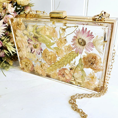 Floral-themed clutch bag with a gold chain on a white surface