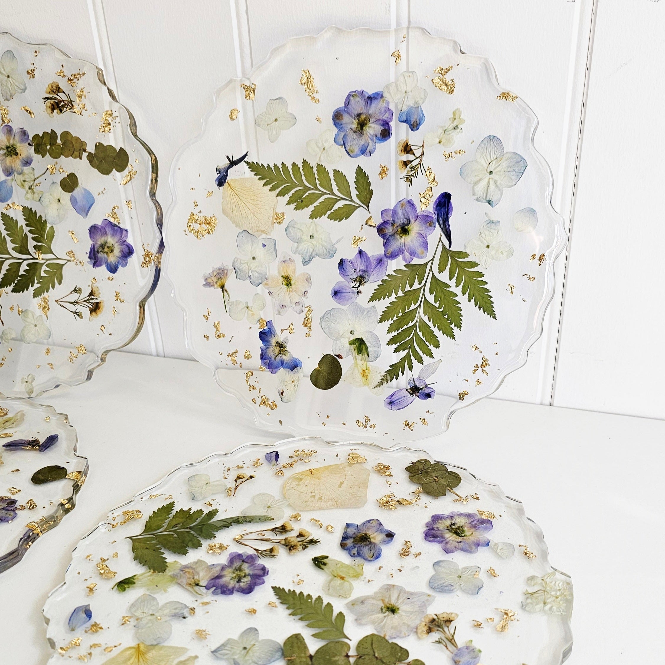 Decorative resin placemats with pressed blue flowers on a white surface 
