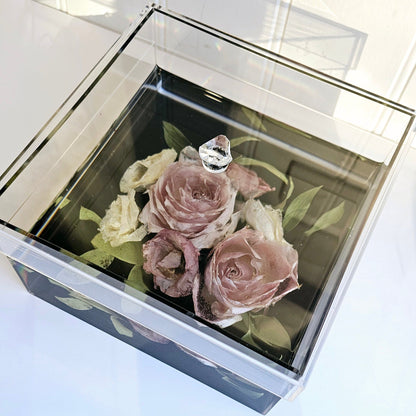 Preserved roses in a resin and acrylic  box on a white surface