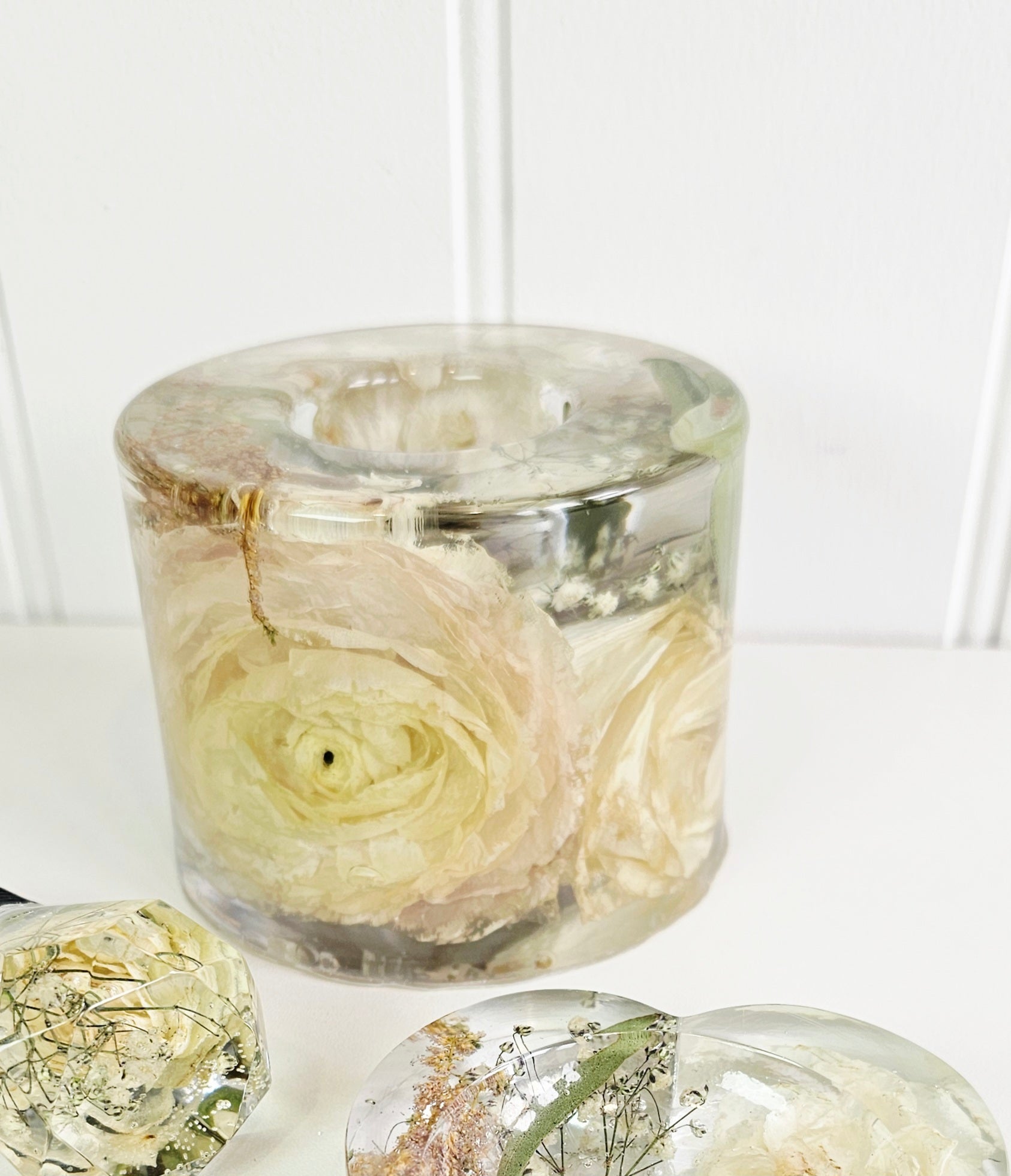 resin cylinder tealight holder with preserved flowers on a white background