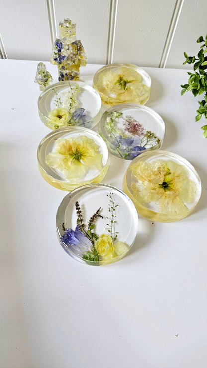 Set of clear resin coasters with pressed flowers on a white surface