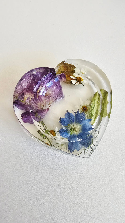 Heart-shaped paperweight with pressed flowers on a white background