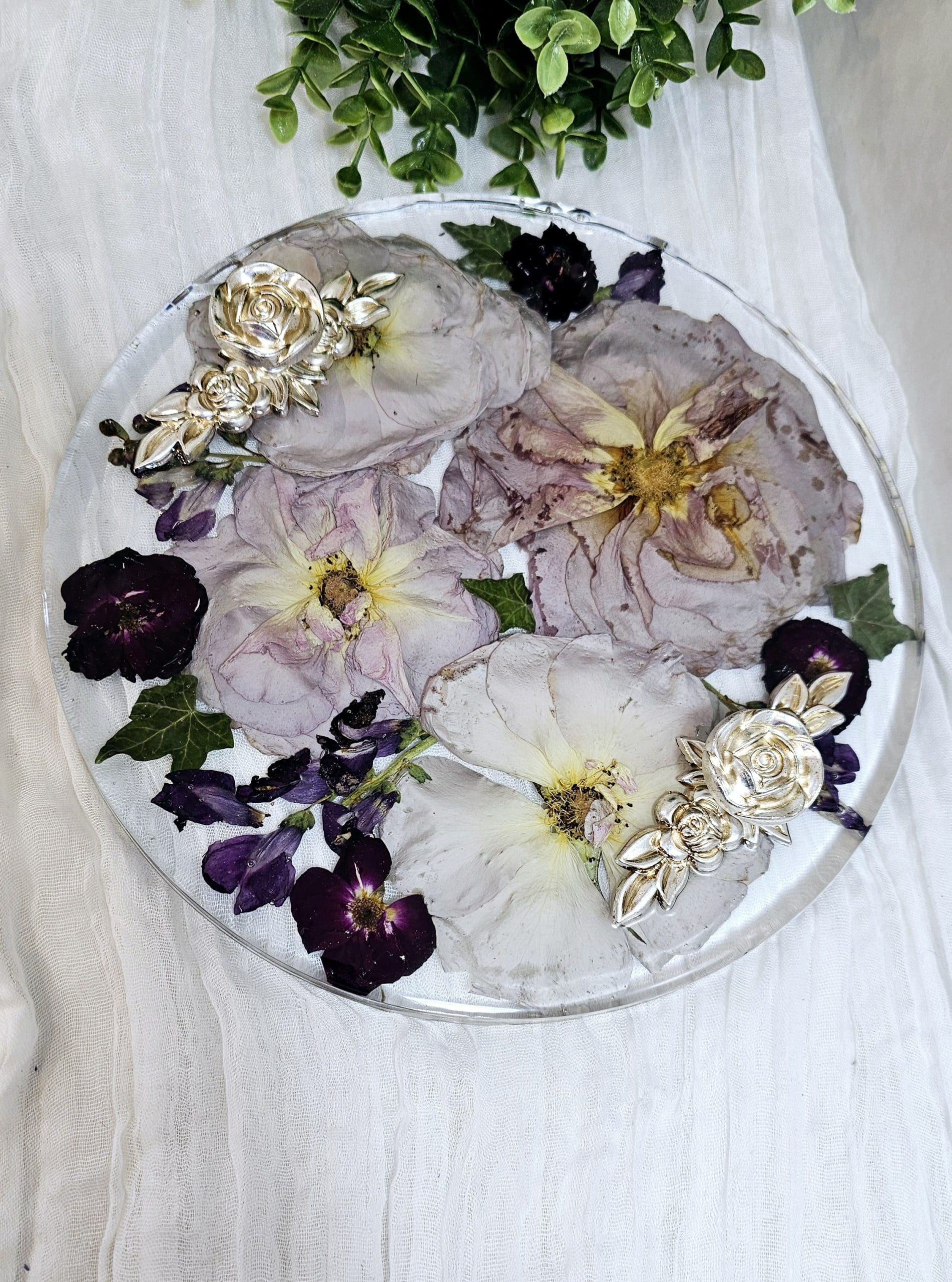 round resin wedding flower preservation tray with fancy handles on a white fabric background 