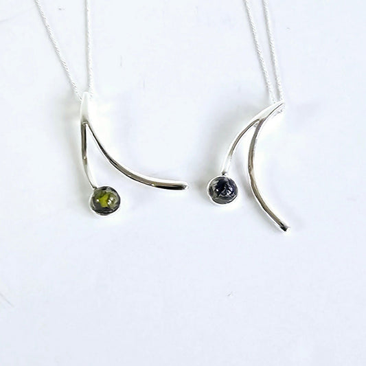 2 sterling silver drop necklaces with flower preserved in resin on one side on a white background 