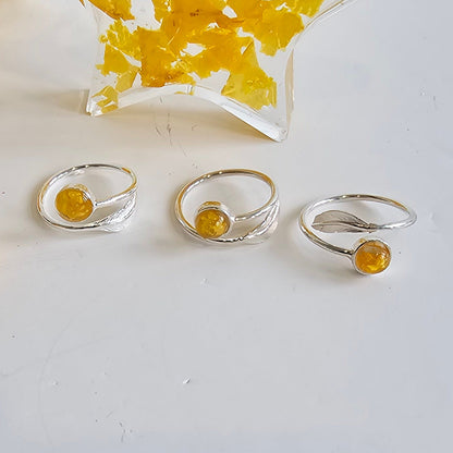 Three silver rings with yellow flower preservation on a white surface