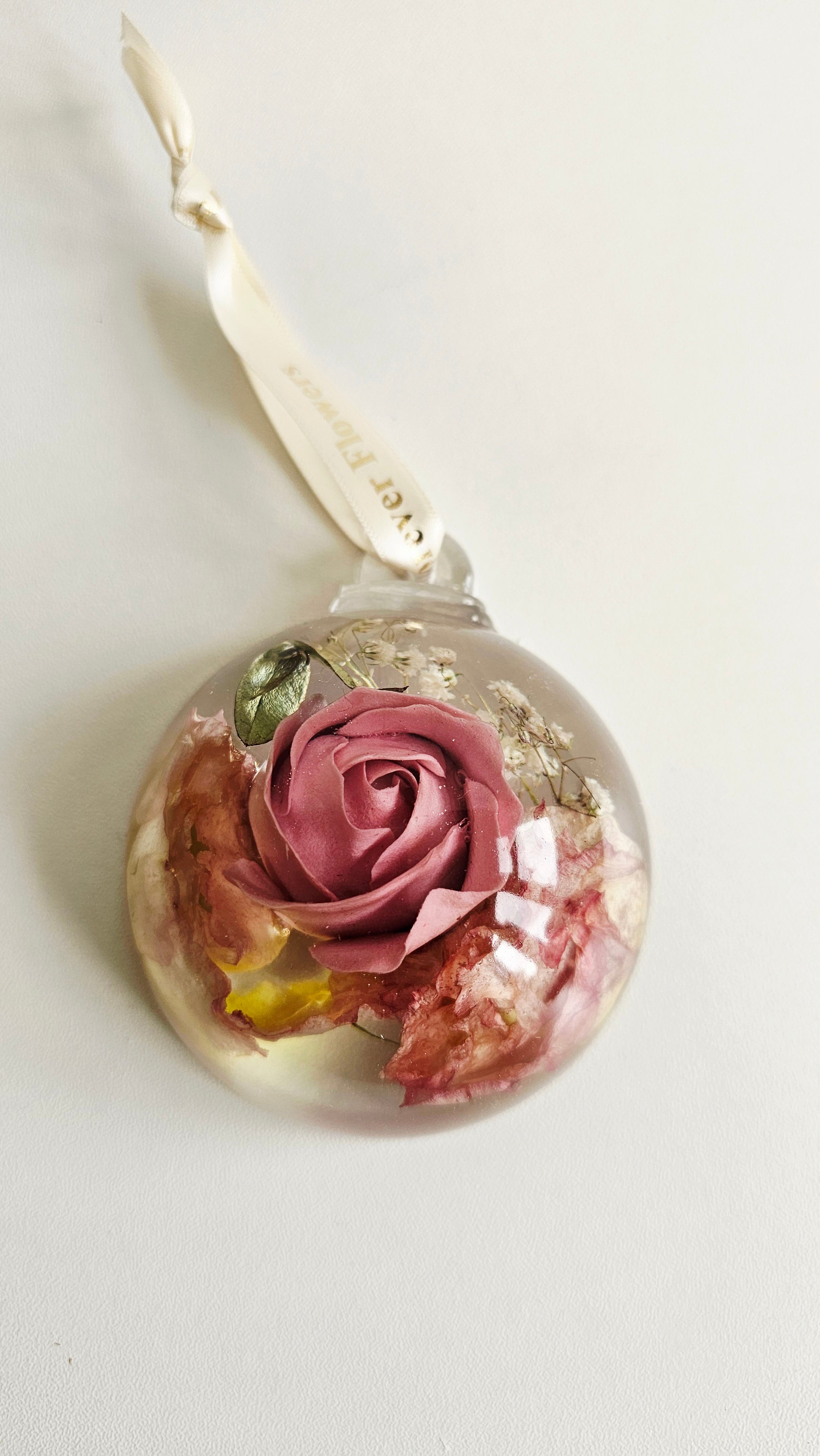 resin flower preservation bauble with a pink rose inside on a white background