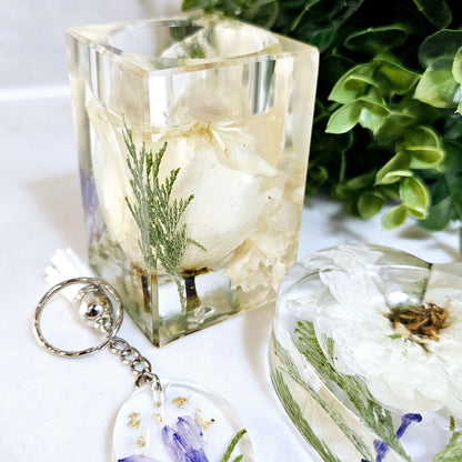 Clear resin block tealight holder  with floral designs and a keychain with a similar design on a white background.