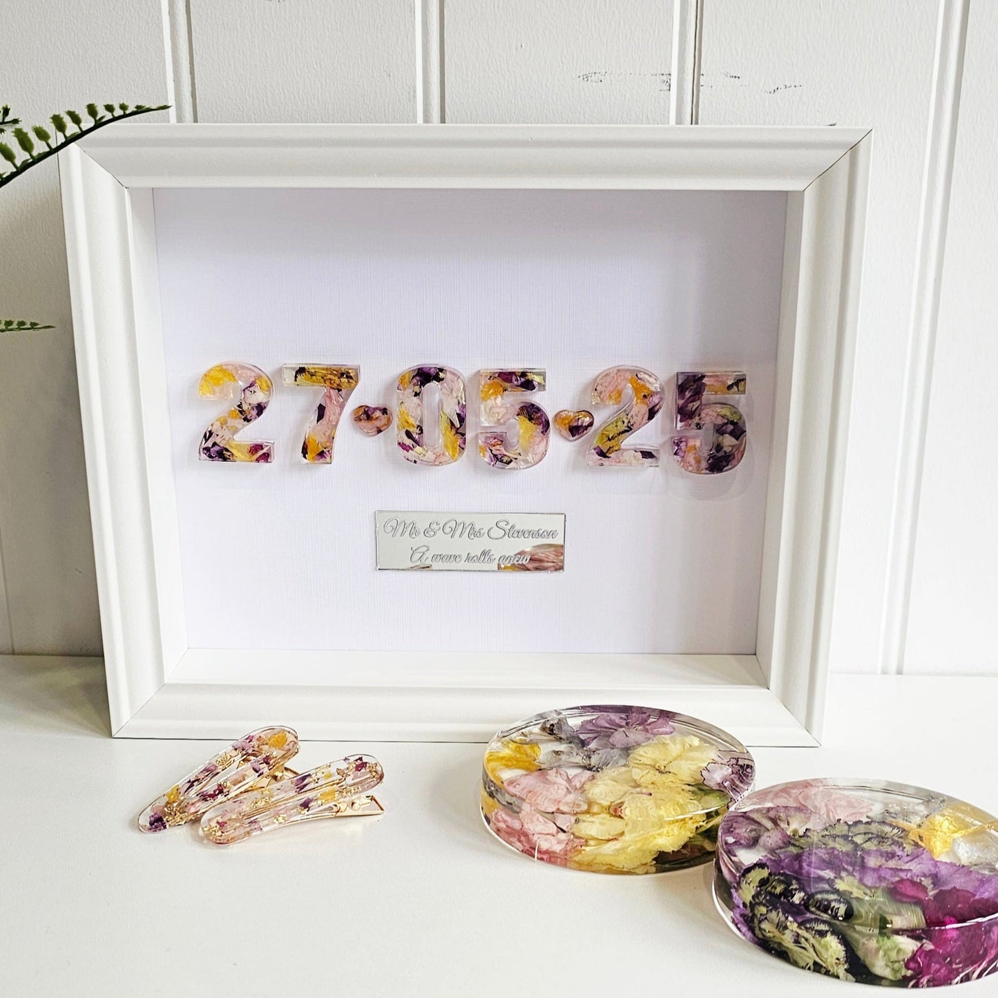 Decorative items including a framed date with floral designs on a white surface.