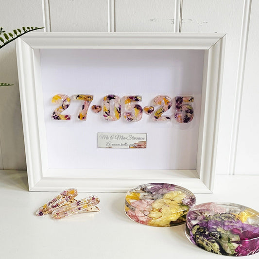 Decorative items including a framed date with floral designs on a white surface.
