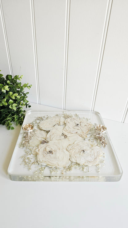 Decorative tray with floral design on a white surface with a plant in the background