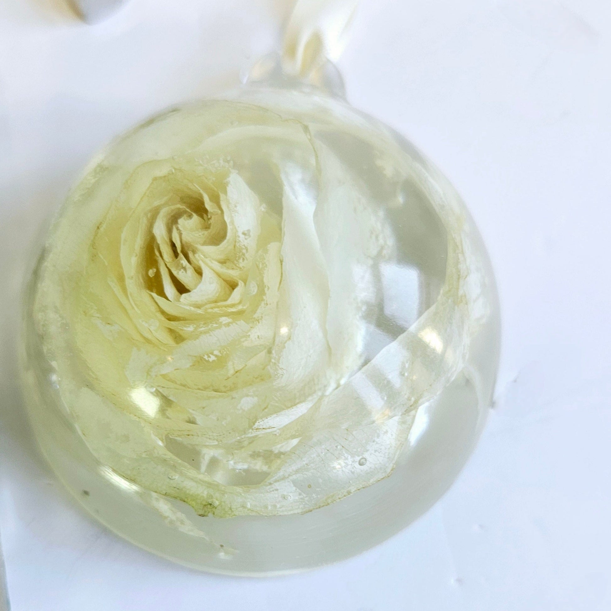 Clear resin bauble with a rose design on a white background