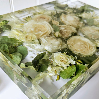 Decorative resin block preserved flowers and greenery on a white surface