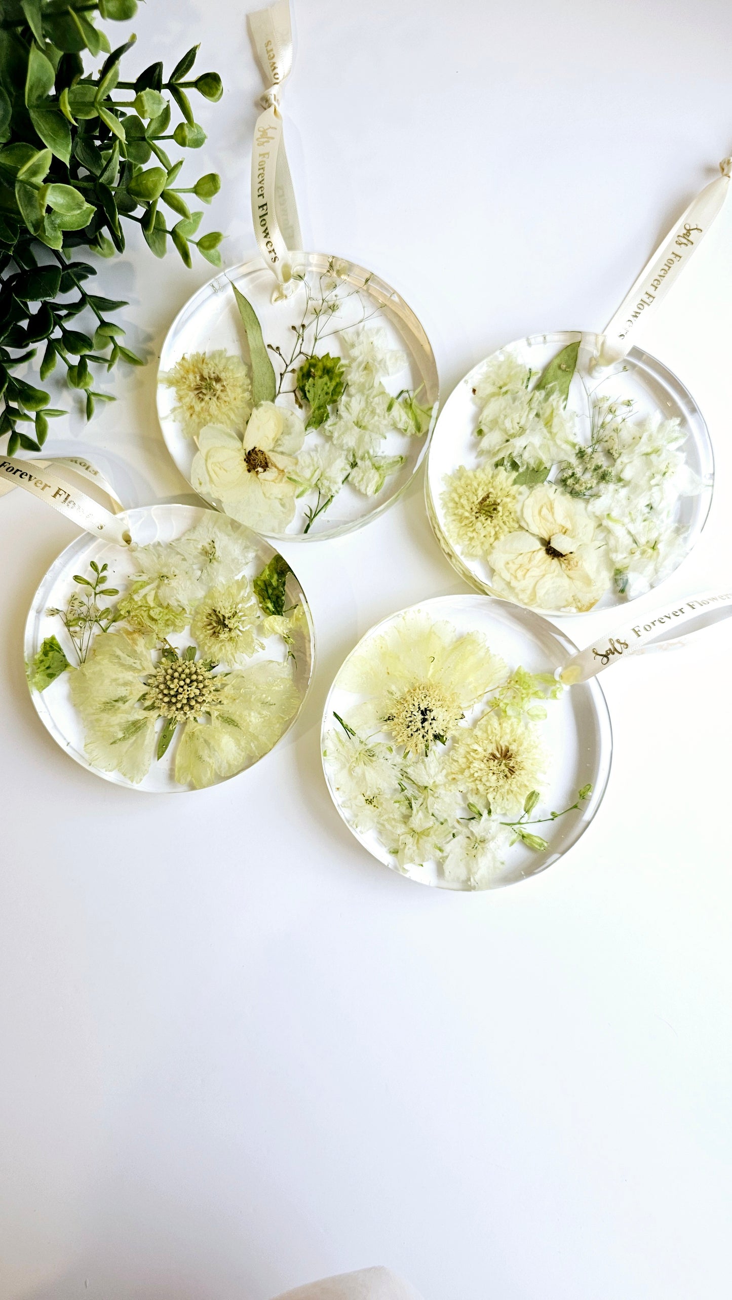 resin decorative hanging disks with pressed flowers on a white surface