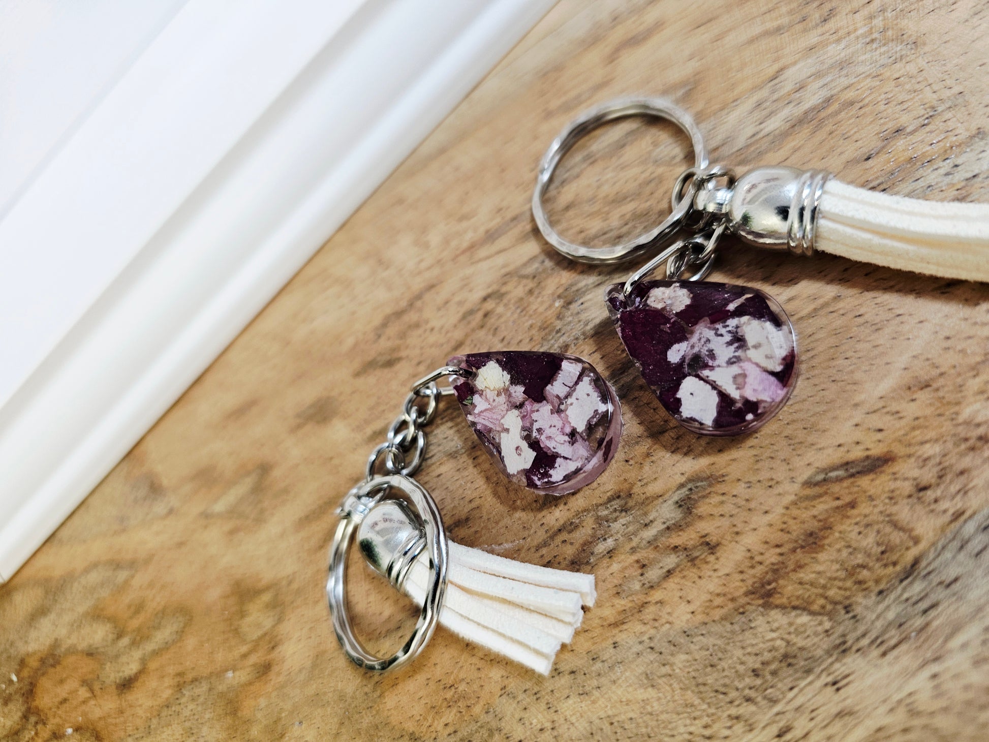 resin keychain with purple teardrop shaped charm and tassel on a wooden surface