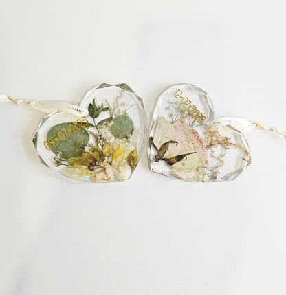Heart-shaped resin pieces with pressed flowers and leaves on a white background